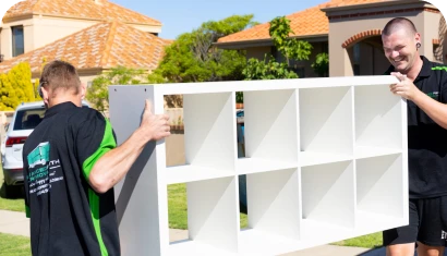 Two Advanced Perth Removals movers carrying a white shelving unit